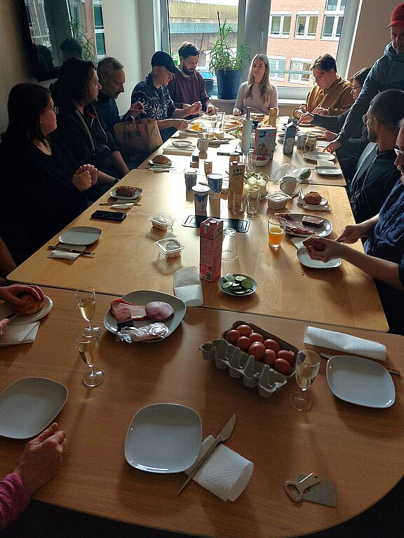 Team heyday sitzt zum Frühstück um den großen Küchentisch herum.