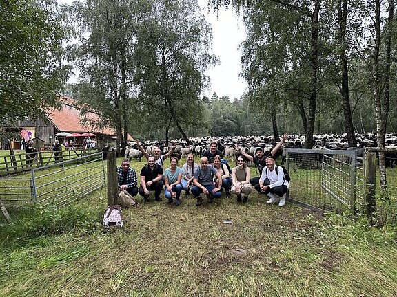 Unser Team hockt geschafft aber glücklich vor dem Gehege, in das wir die Schafsherde geführt haben.